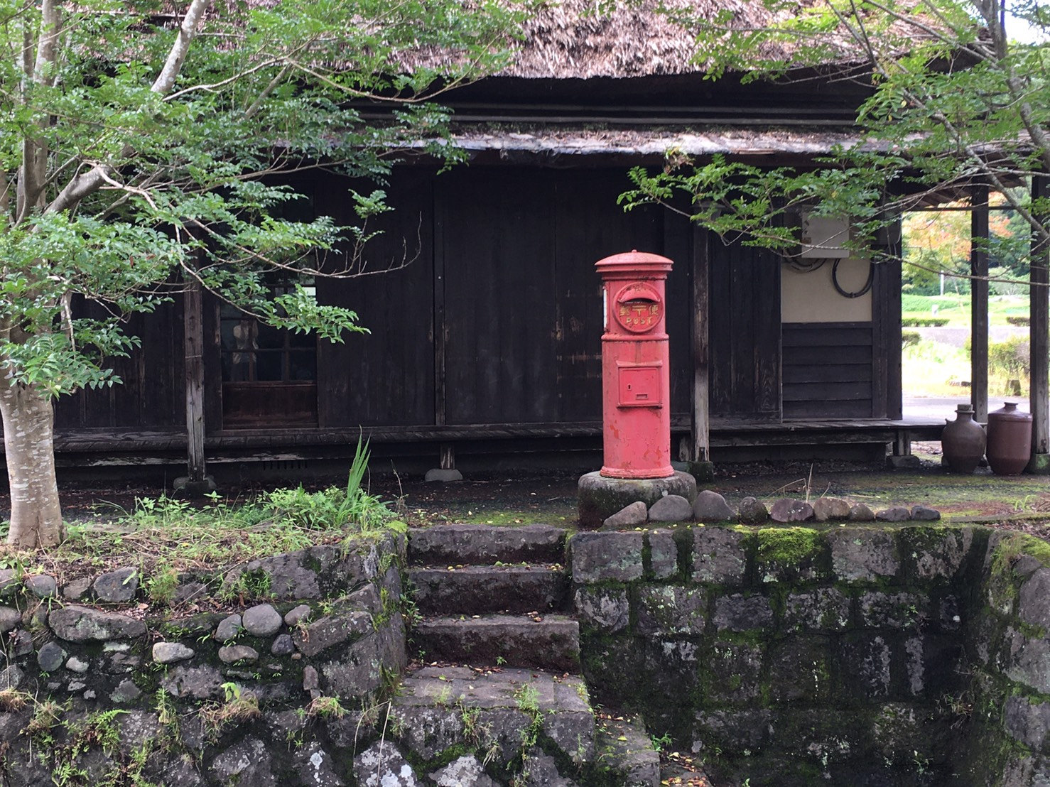 原尻の滝の近くの茅葺き屋根の建物と赤い丸型ポスト