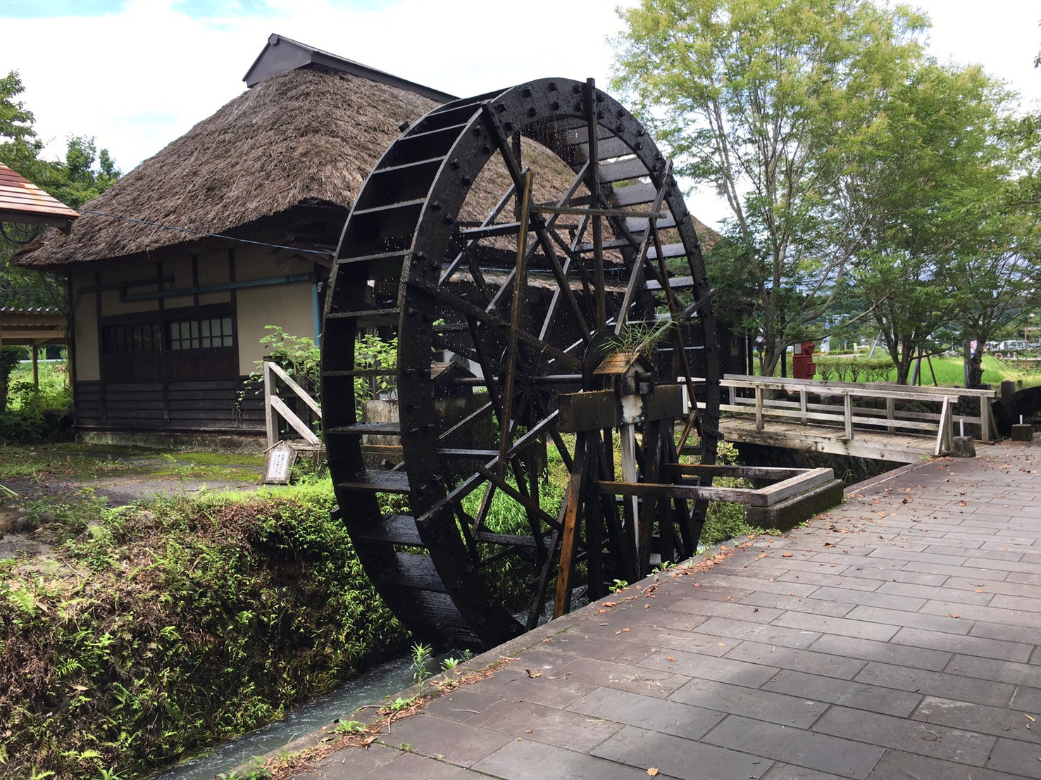 原尻の滝の近くにある大きな木製の水車と茅葺き屋根の建物