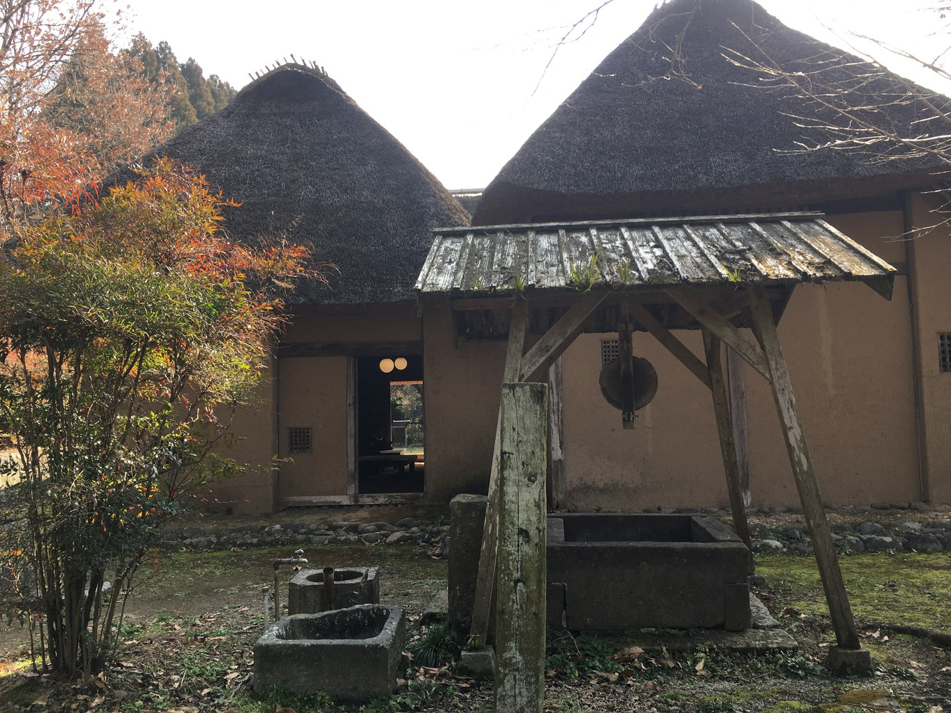 肥後民家村の茅葺き屋根の建物と井戸のような設備