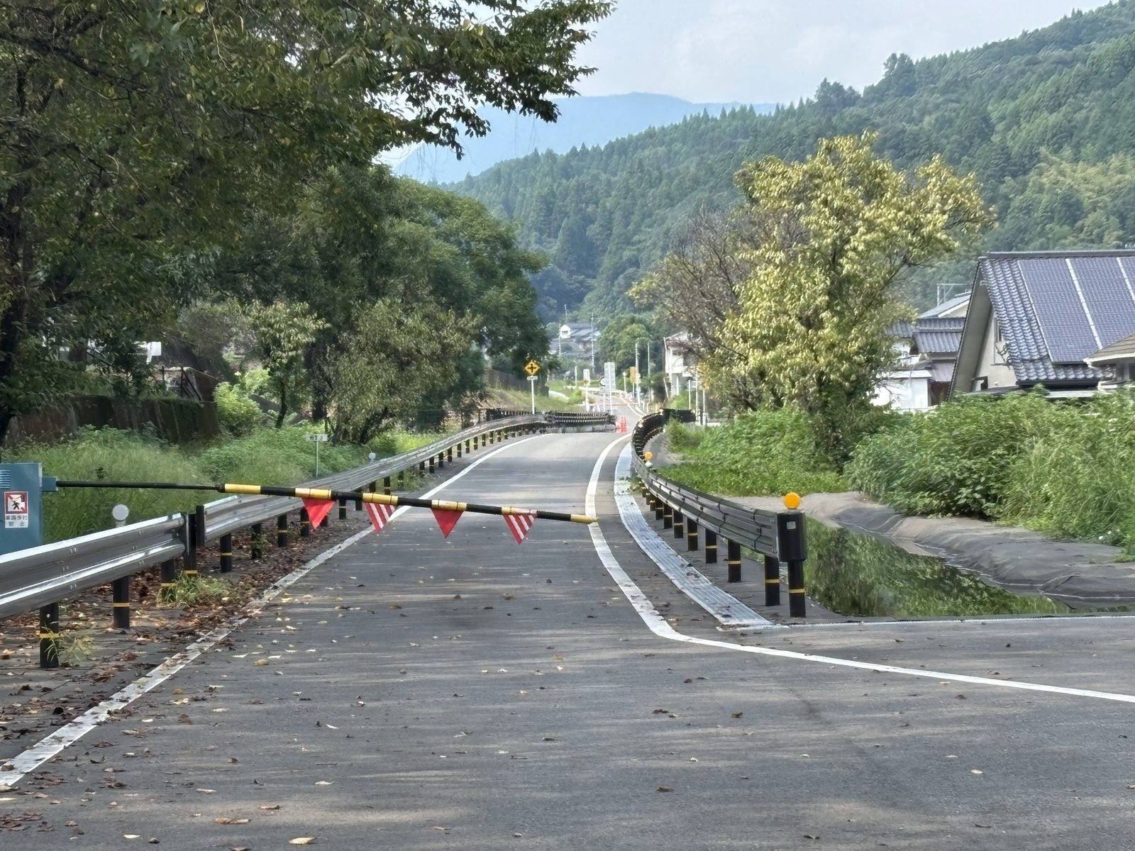 宝珠山駅付近のBRT専用道入口にある遮断機と山あいに続く道