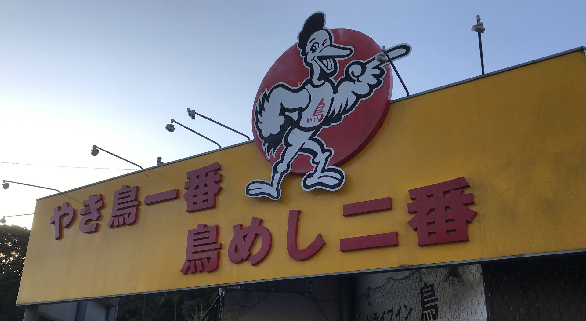 ドライブイン鳥伊万里本店の黄色い店頭看板と鳥のイラスト