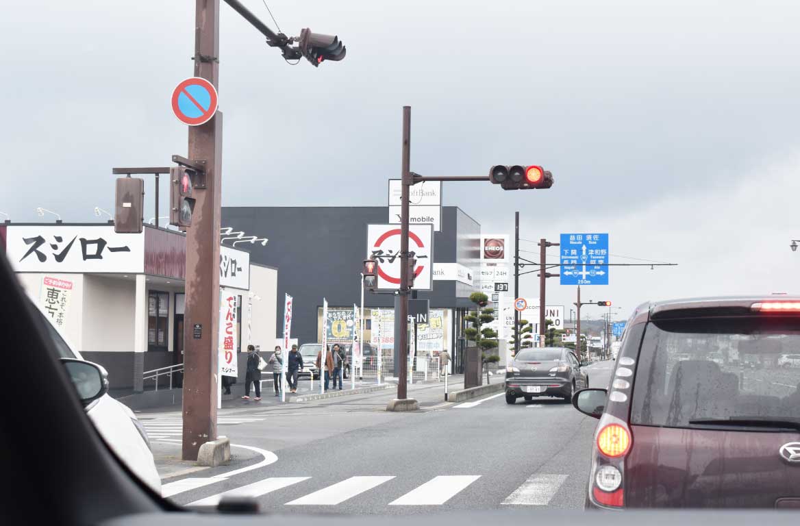 萩市内の交差点。店舗の看板や街並みが見える