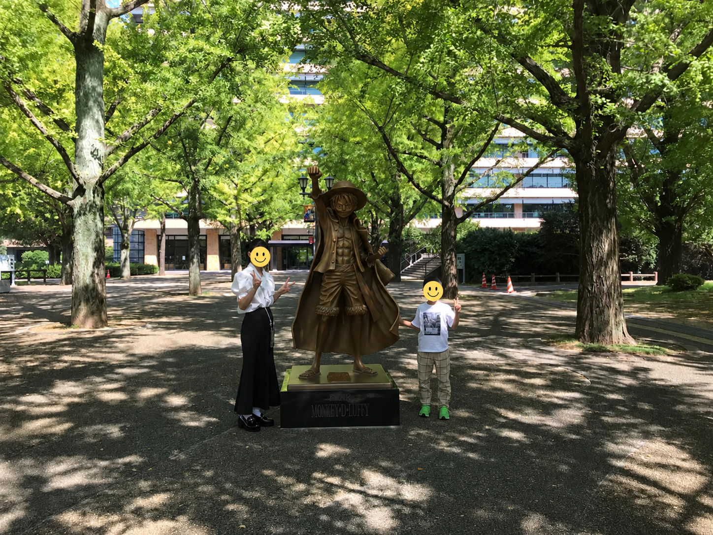 熊本県庁のルフィ像と並んで記念撮影する子どもたち（顔はスタンプで加工済み）