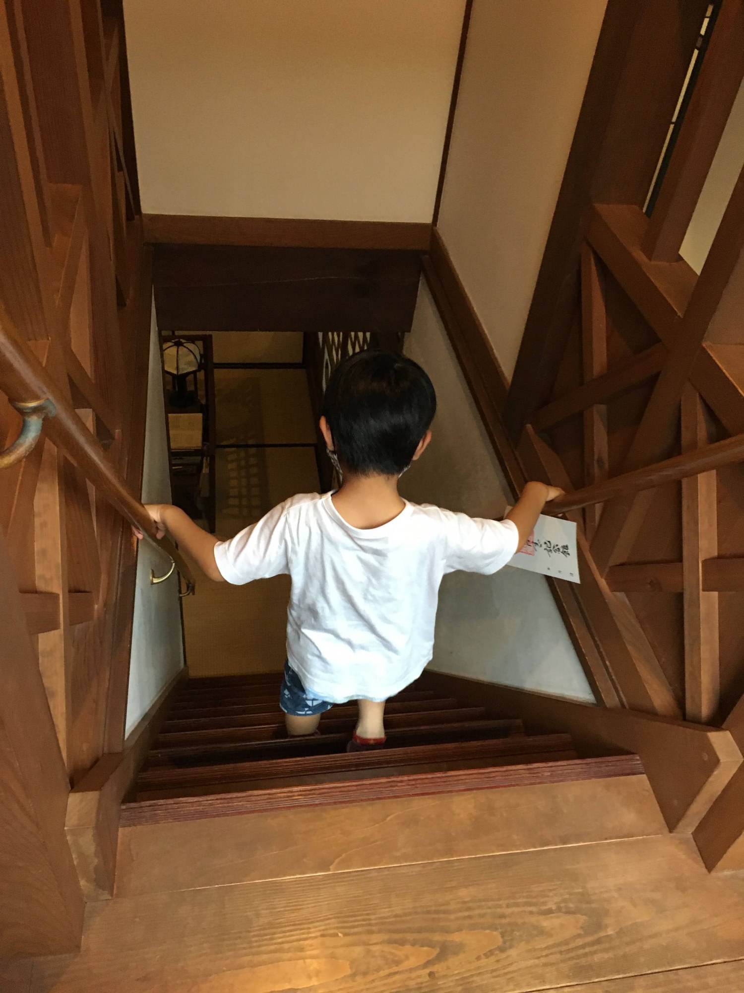 金子文英堂の木の階段を降りる子どもの後ろ姿