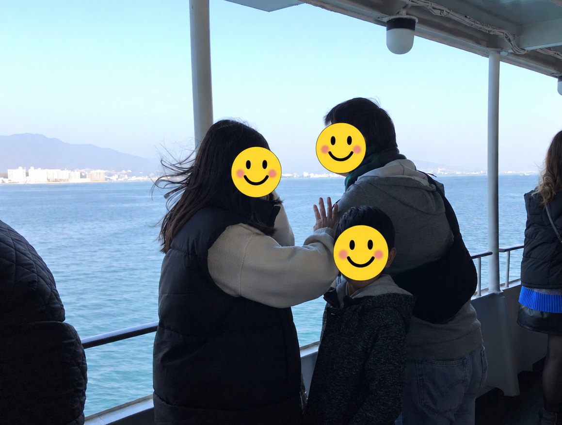 宮島へ渡るフェリーのデッキから海を眺める家族の写真